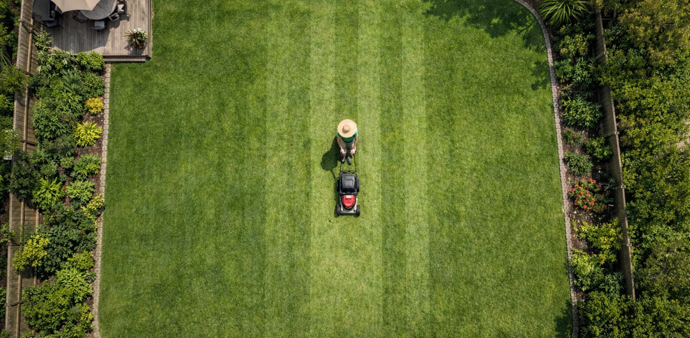 Aerial view of a lawn care professional mowing a striped green lawn