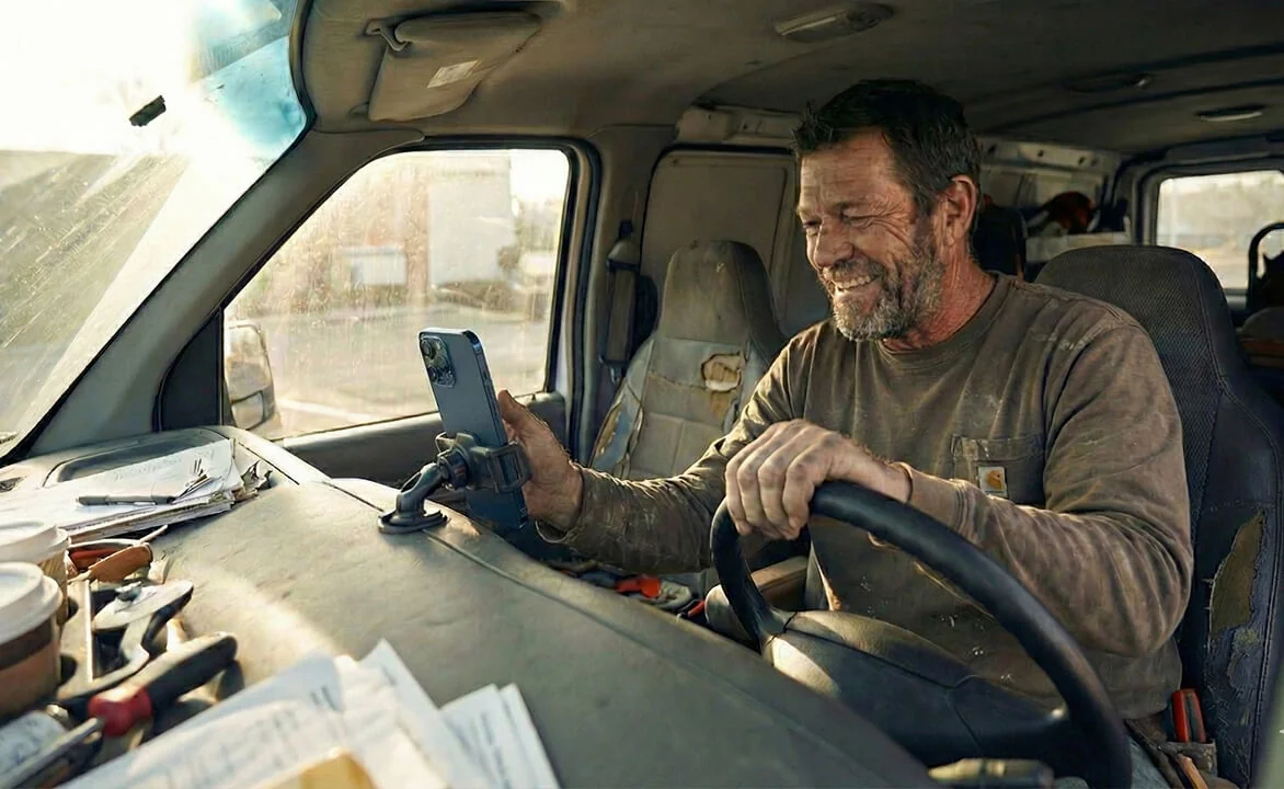 Man setting his phone to the phone holder in his work van, preparing to drive to the next job.